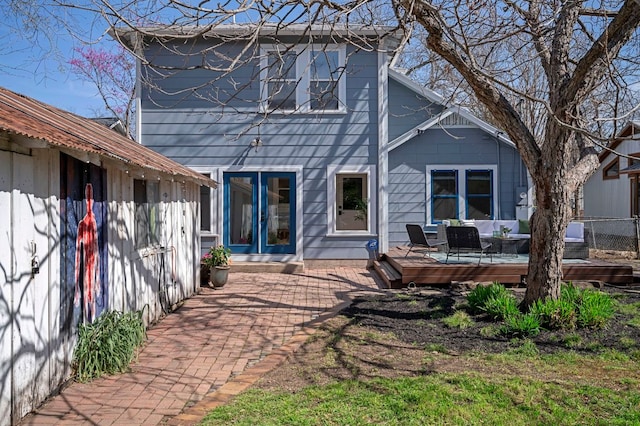 rear view of property featuring french doors, a deck, and fence