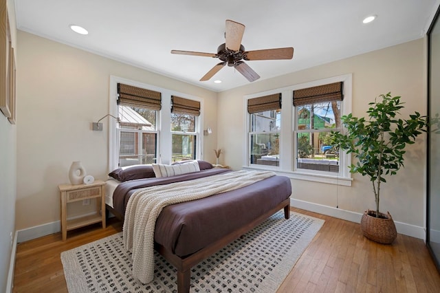 bedroom featuring multiple windows, baseboards, and light wood-style floors