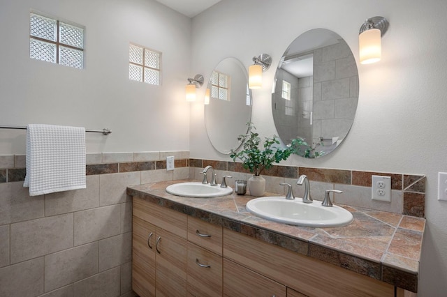 full bath featuring double vanity, tile walls, and a sink