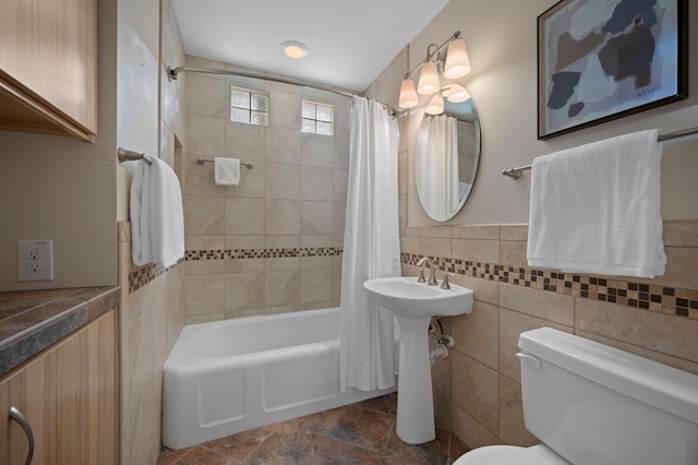 full bathroom featuring tile walls, shower / bath combination with curtain, toilet, and a wainscoted wall