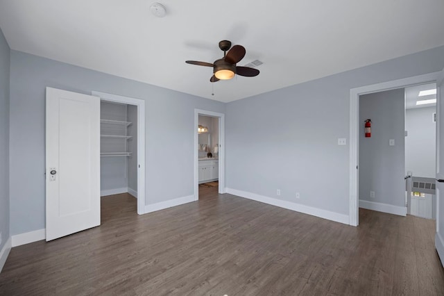 unfurnished bedroom featuring a walk in closet, wood finished floors, and baseboards