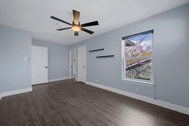 empty room with visible vents, ceiling fan, dark wood-type flooring, and baseboards