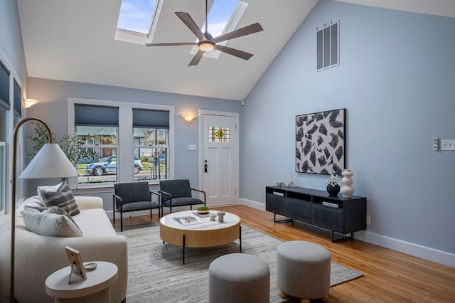 living room featuring visible vents, a skylight, a ceiling fan, and wood finished floors