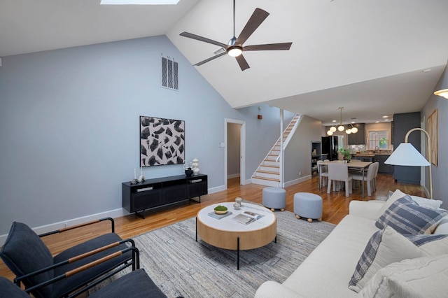 living area with stairs, light wood-style flooring, ceiling fan with notable chandelier, and visible vents