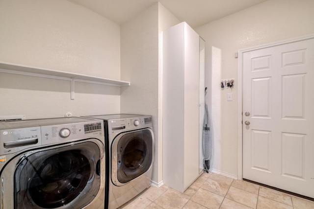 washroom featuring laundry area, light tile patterned floors, washing machine and dryer, and baseboards