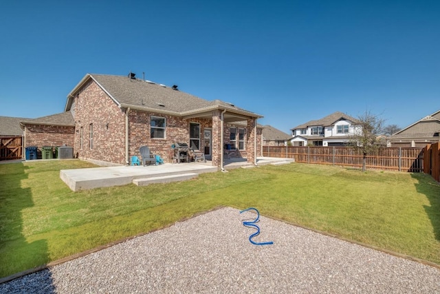 back of house featuring cooling unit, fence, brick siding, a patio area, and a lawn