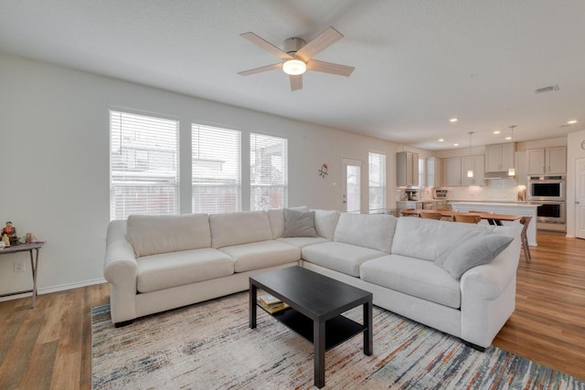 living area featuring light wood-type flooring, visible vents, recessed lighting, baseboards, and ceiling fan