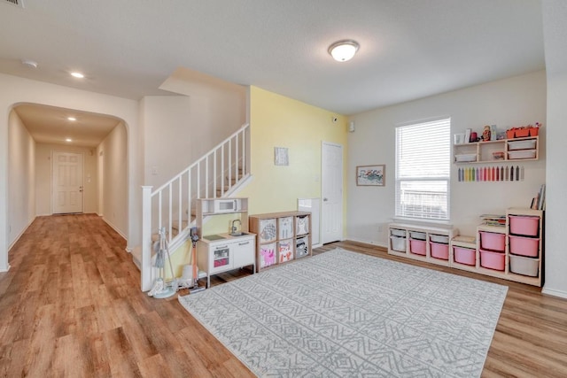 game room with arched walkways, baseboards, and wood finished floors