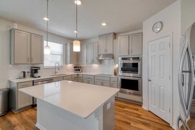1004 Brenham Ln, Leander, TX 78641 - kitchen featuring appliances with stainless steel finishes, gray cabinets, under cabinet range hood, decorative backsplash, and recessed lighting