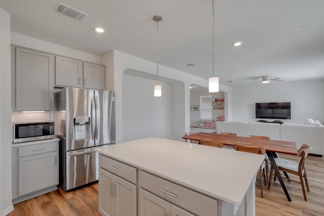 kitchen featuring visible vents, gray cabinetry, light wood-style floors, appliances with stainless steel finishes, and tasteful backsplash