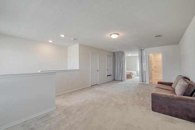 living room with a textured ceiling, baseboards, visible vents, and light carpet