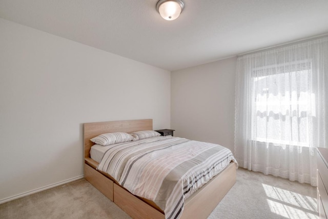 bedroom with light carpet and baseboards