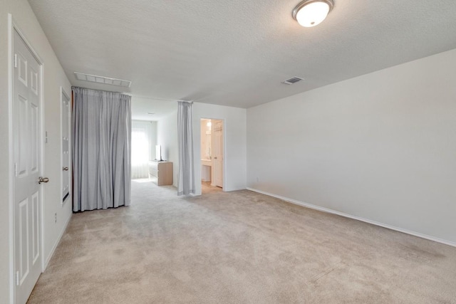 1004 Brenham Ln, Leander, TX 78641 - unfurnished bedroom with light carpet, a textured ceiling, and ensuite bath