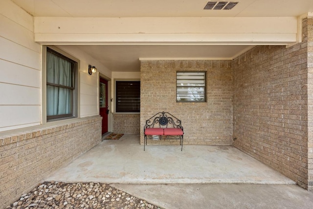 property entrance with visible vents and brick siding