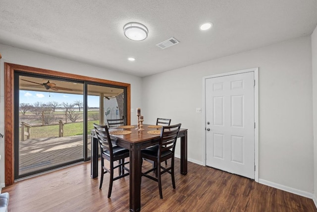 dining room featuring dark wood-style floors, visible vents, a textured ceiling, and baseboards