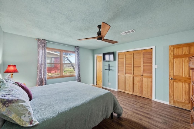 bedroom featuring visible vents, baseboards, dark wood finished floors, a textured ceiling, and a ceiling fan