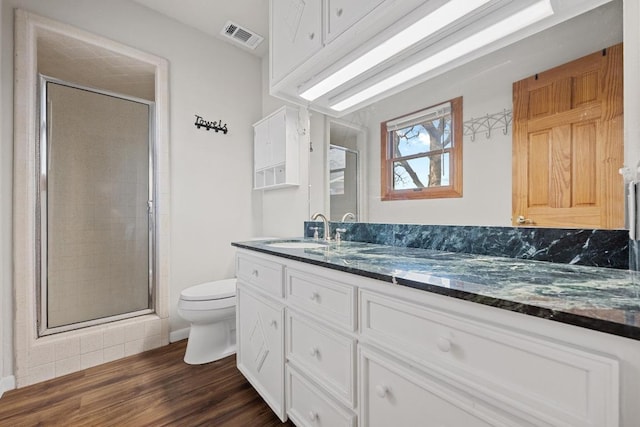 bathroom with visible vents, toilet, a stall shower, wood finished floors, and vanity