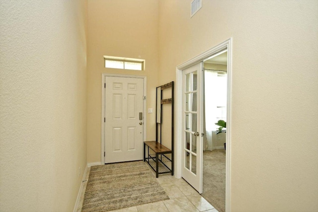 entryway featuring light tile patterned floors, visible vents, french doors, and a high ceiling