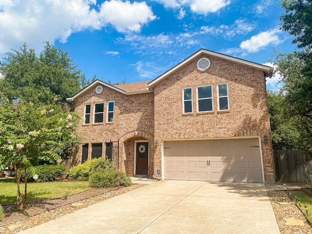 traditional home with brick siding, concrete driveway, an attached garage, and fence