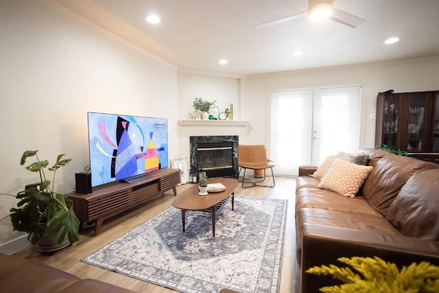 living room with crown molding, a ceiling fan, and wood finished floors