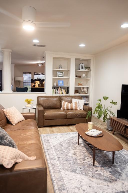 living room with recessed lighting, wood finished floors, visible vents, and built in shelves