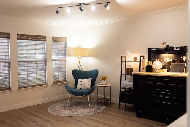 sitting room with wood finished floors, baseboards, ornamental molding, and a dry bar