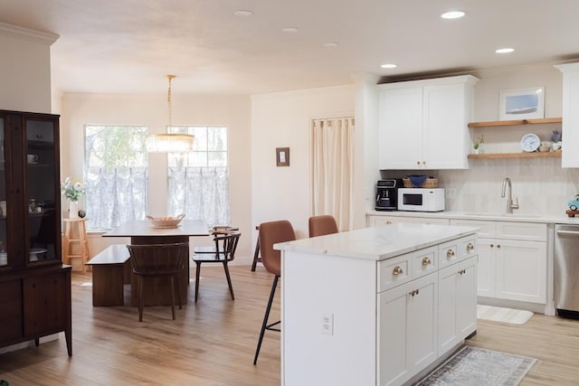 kitchen featuring a sink, tasteful backsplash, a center island, white microwave, and dishwasher