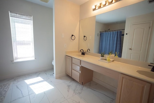 full bathroom with a sink, baseboards, marble finish floor, and double vanity