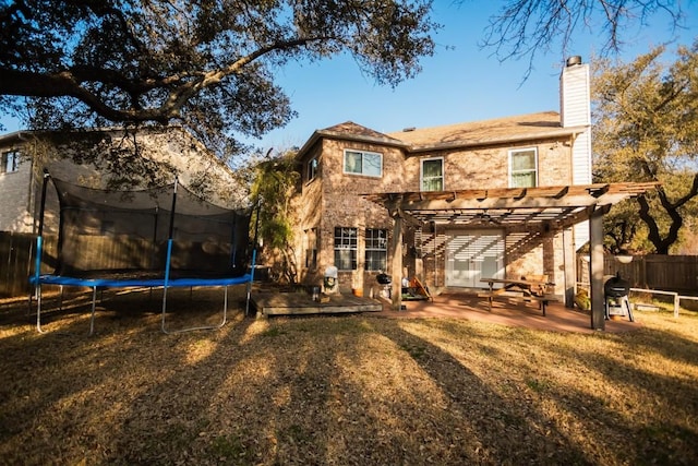 rear view of house featuring fence, a pergola, a chimney, a trampoline, and a patio area