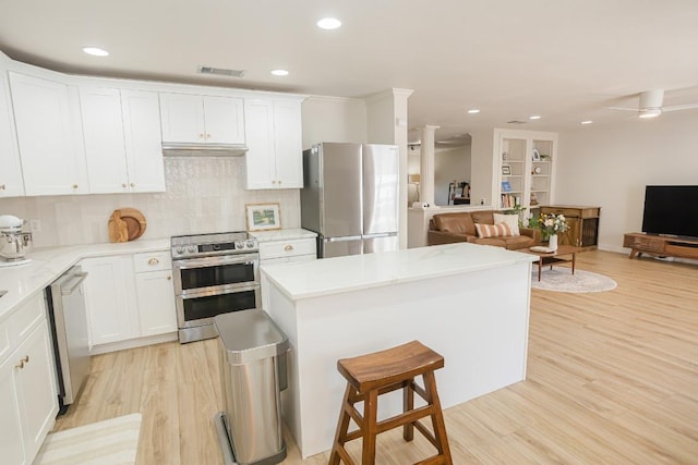 kitchen with stainless steel appliances, open floor plan, light wood-style flooring, backsplash, and recessed lighting
