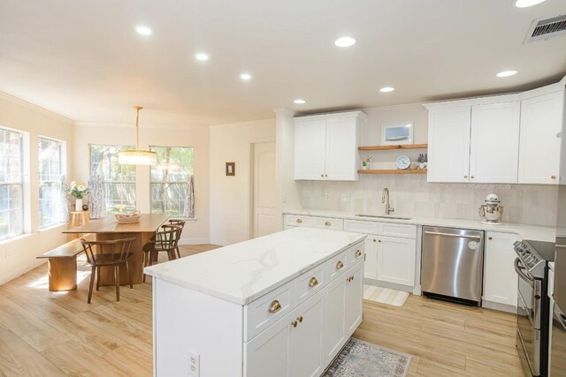 kitchen with appliances with stainless steel finishes, a sink, light wood-style floors, a center island, and crown molding