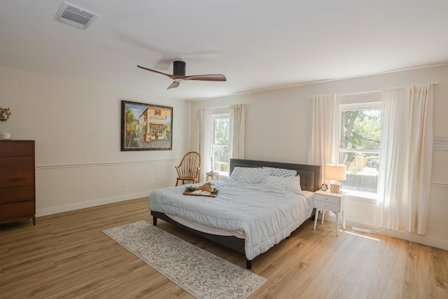 bedroom with multiple windows, wood finished floors, and baseboards