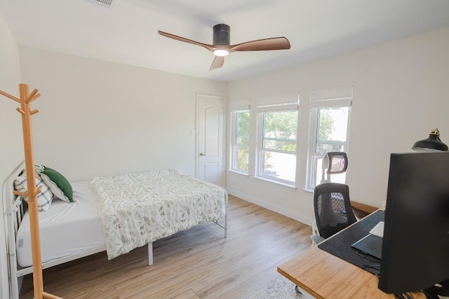 bedroom featuring light wood-type flooring, a desk, baseboards, and ceiling fan