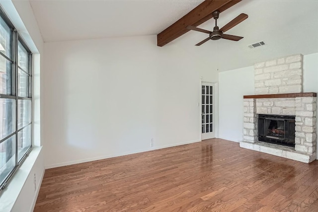 unfurnished living room featuring visible vents, a ceiling fan, wood finished floors, a fireplace, and vaulted ceiling with beams