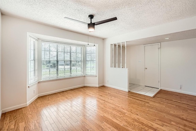 empty room with baseboards, a textured ceiling, a ceiling fan, and wood finished floors