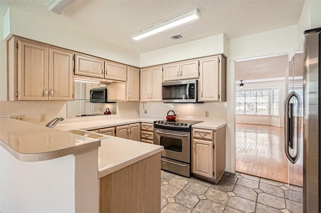 kitchen featuring visible vents, appliances with stainless steel finishes, light countertops, and a peninsula