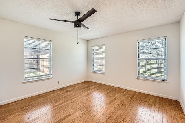 empty room with hardwood / wood-style floors, a textured ceiling, baseboards, and ceiling fan