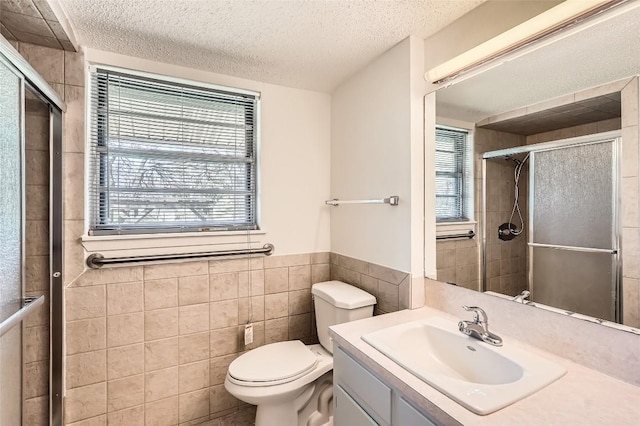 bathroom with a wealth of natural light, a textured ceiling, a stall shower, and toilet