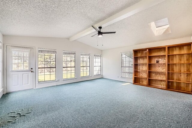 empty room with vaulted ceiling with skylight, a textured ceiling, ceiling fan, and carpet flooring