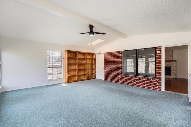 empty room with lofted ceiling with beams, carpet floors, a fireplace, a textured ceiling, and a ceiling fan