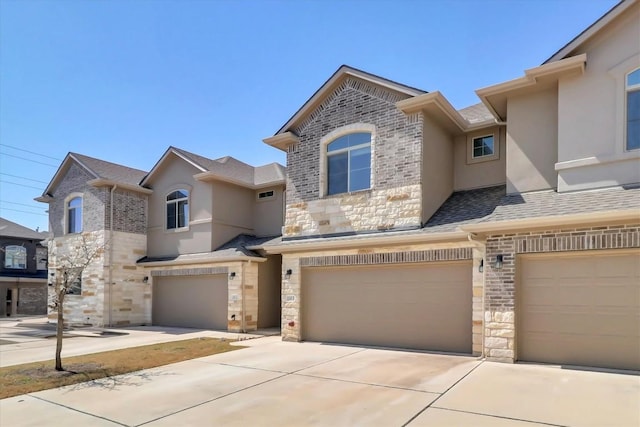 view of property featuring a garage, stone siding, concrete driveway, and stucco siding