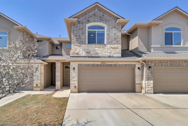 multi unit property featuring brick siding, stucco siding, a garage, stone siding, and driveway