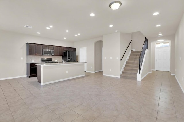 kitchen featuring stainless steel microwave, backsplash, open floor plan, light countertops, and black fridge with ice dispenser