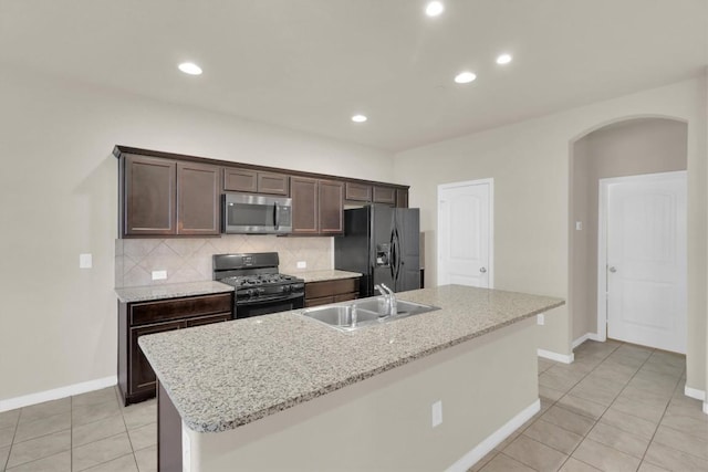 kitchen with tasteful backsplash, dark brown cabinets, arched walkways, black appliances, and a sink