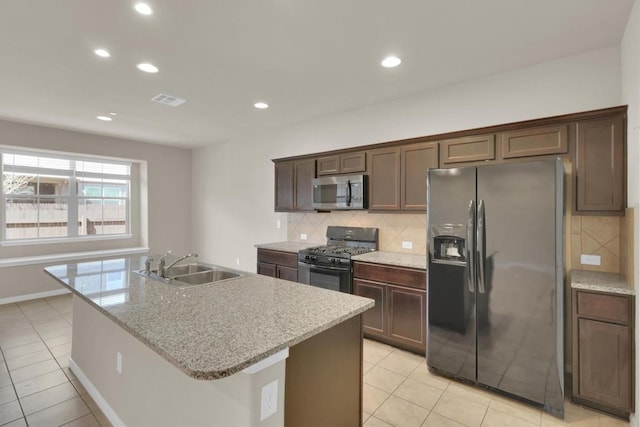 kitchen featuring fridge with ice dispenser, a sink, stainless steel microwave, range with gas cooktop, and decorative backsplash