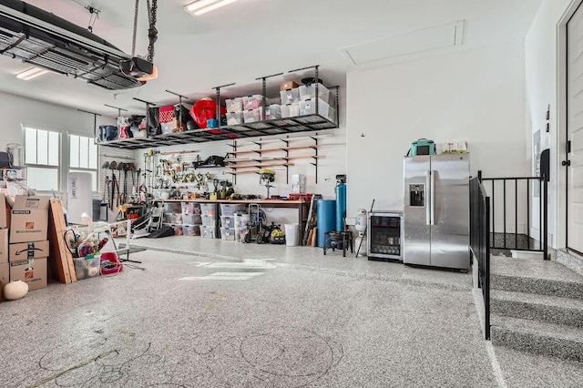 garage with a garage door opener and stainless steel fridge with ice dispenser