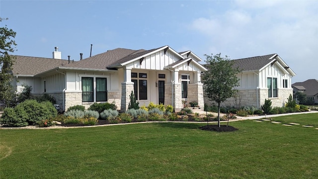 view of front of home with board and batten siding, a front lawn, stone siding, and a chimney