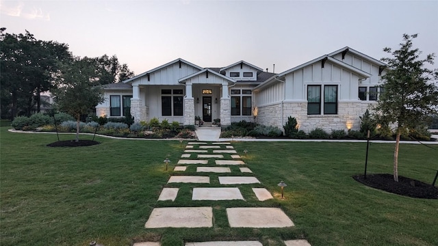 craftsman house featuring board and batten siding, a front lawn, and stone siding