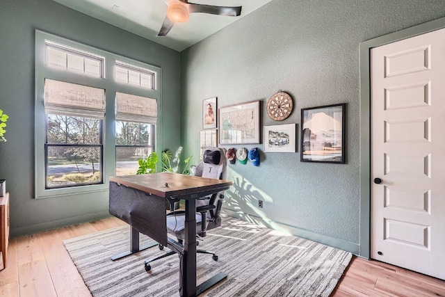 home office with a textured wall, baseboards, and light wood finished floors