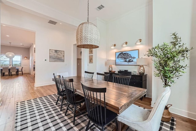 dining area with visible vents, baseboards, light wood-style floors, and crown molding